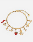Ein Armband mit Anhängern aus einer Goldkette von Princess Goes Hollywood mit Karabinerverschluss, sieben Anhängern – darunter ein Erdbeer-Anhänger –, Kristallakzenten und einem runden goldenen Anhänger. Ein verspieltes Accessoire, das in jeder Edelstahlschmuck-Kollektion funkelt.