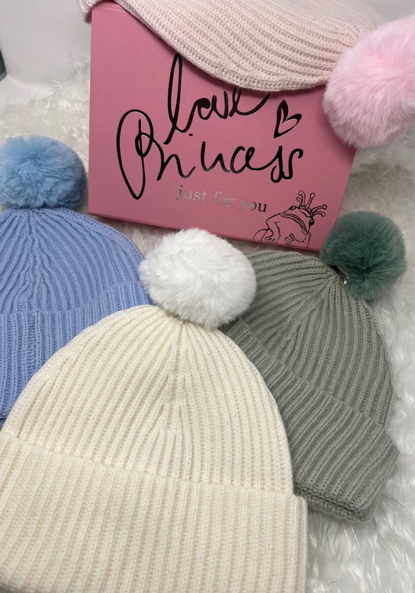 Four Princess Goes Hollywood Wolle Kaschmir Mützen—blue, cream, gray, and pink with flauschigem Bommel—surround a pink box reading “love Princess just for you,” all set on a soft white surface.