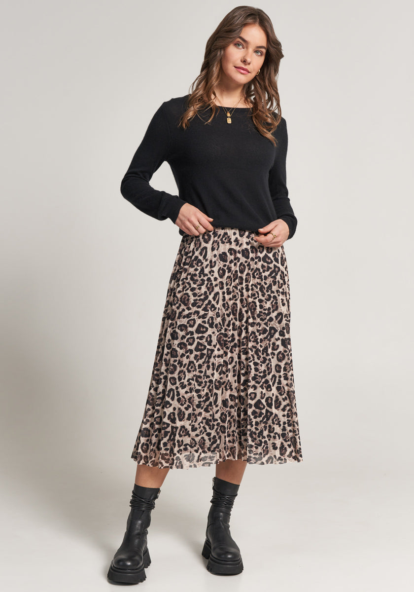 A woman with wavy brown hair wears a Princess Goes Hollywood Rundhals Kaschmir Pullover tucked into a pleated leopard-print midi skirt, paired with black ankle boots and a gold pendant necklace. She stands against a plain background, smiling softly.