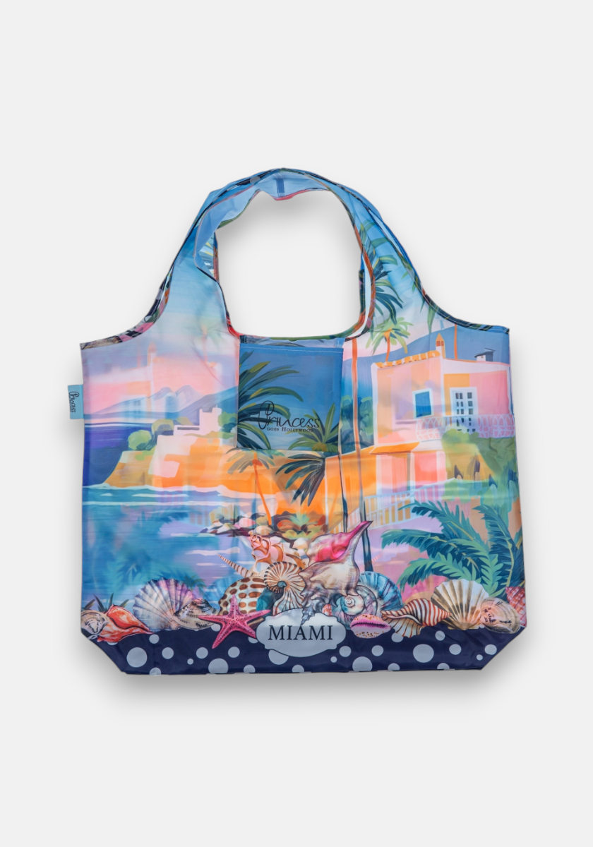 The Shopper Miami by Princess Goes Hollywood is a colorful, foldable tote bag made from recycled PET, featuring a vibrant allover Miami print with palm trees, pastel buildings, seashells, waves, and matching handles.