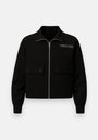 A black zip-up sweatjacket by Princess Goes Hollywood features two front flap pockets, a shirt-style collar, ribbed cuffs, and "PRINCESS" embroidered in white on the left chest. Its minimalist design stands out against a white background.