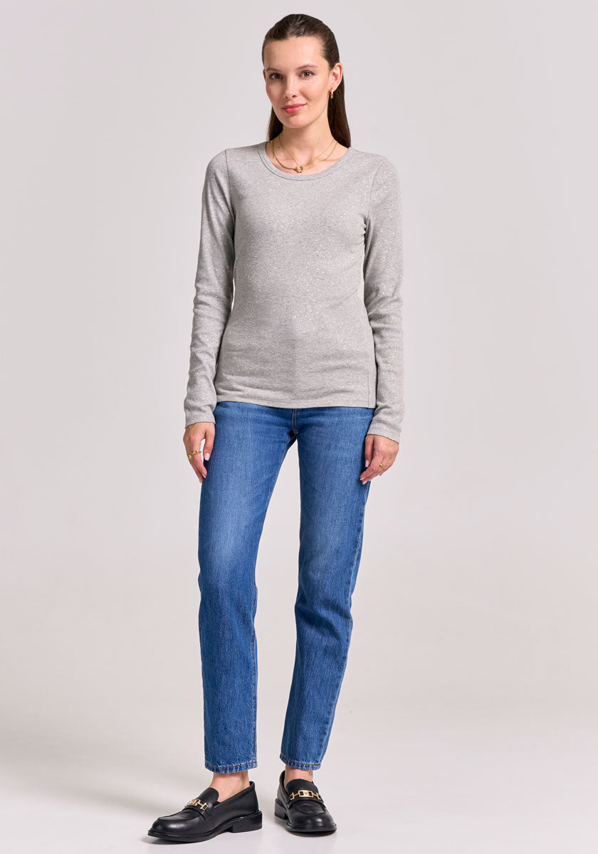 A woman with light skin and straight brown hair pulled back stands facing forward against a light grey background. She wears a fitted grau Baumwoll-Shirt mit Stretchanteil from Princess Goes Hollywood, blue jeans, and black loafers.