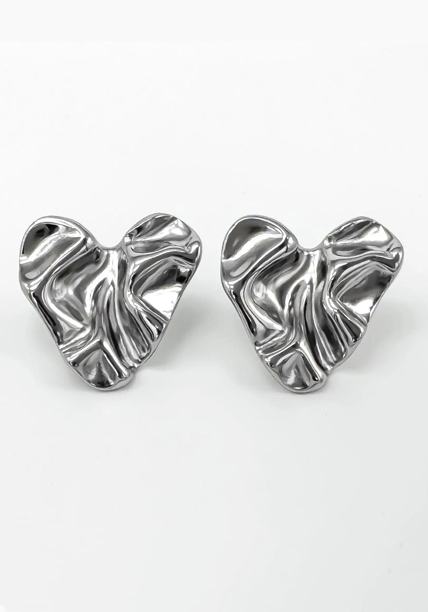 A pair of shiny, silver-toned Edelstahl Ohrstecker by Princess Goes Hollywood, shaped like abstract crumpled hearts. Their organische Form and wavy texture create a glänzende Oberfläche that beautifully reflects light.