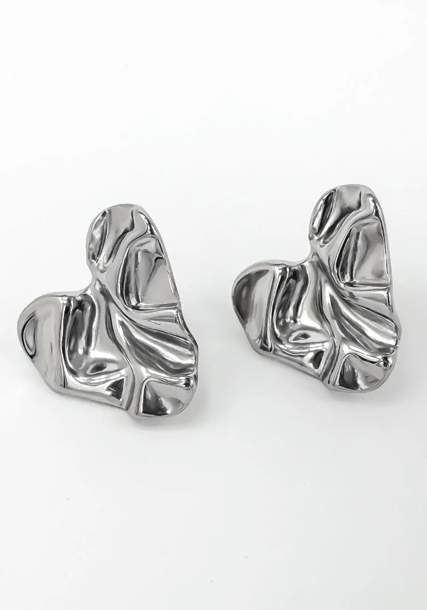 A pair of abstract, silver-toned Edelstahl Ohrstecker by Princess Goes Hollywood, shaped like irregular, crumpled hearts with a glänzende Oberfläche and textured folds. Shown on a plain white background.