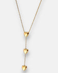 Die goldene Halskette von Princess Goes Hollywood besteht aus einer feinen Edelstahl-Kette mit drei glänzenden Herzanhängern, die vertikal auf einer Seite angeordnet sind und einen eleganten Drop-Effekt erzeugen.