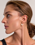 A woman with light skin and brown hair pulled back wears elegant Princess Goes Hollywood black creolen earrings with freshwater pearls on 925 sterling silver. She looks to the left, her natural glow standing out against a plain background.