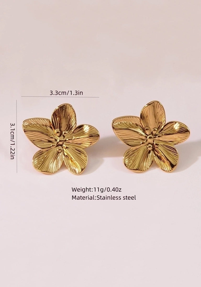 Zwei goldfarbene Edelstahl-Ohrstecker von Princess Goes Hollywood in Form fünfblättriger Blumen (3,3 x 3,1 cm, 11 g) stehen aufrecht vor dezent hellrosa Hintergrund.