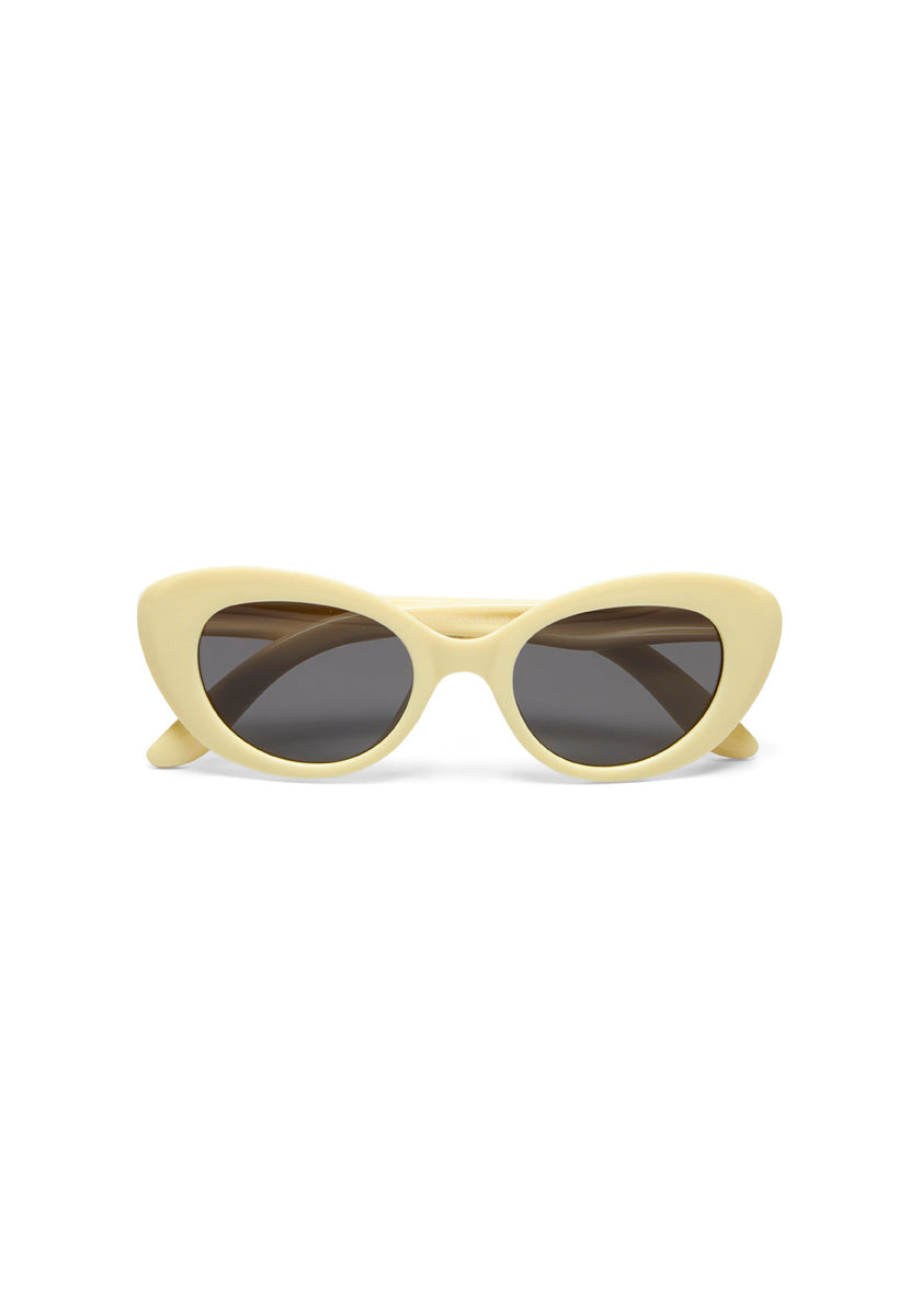 A pair of Okkia Kollektion Parigi sunglasses with an off-white, pale yellow cat-eye frame and dark oval lenses is shown from the front against a white background.