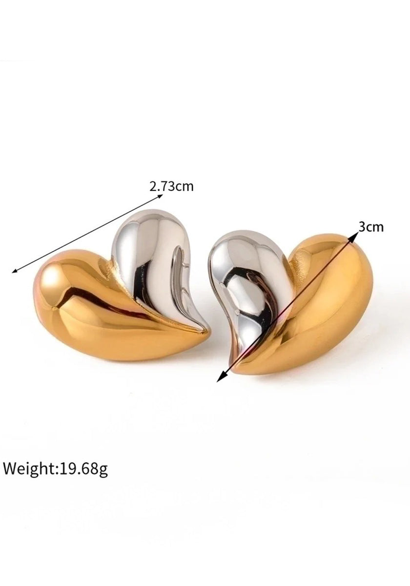 Two metallic heart-shaped earrings by Princess Goes Hollywood in a striking bicolor design—one half gold, one half silver. Each measures 2.73 cm wide and 3 cm tall, weighing 19.68g. Perfect for Herz Ohrstecker fans. Displayed on a white background.