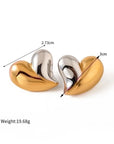 Two metallic heart-shaped earrings by Princess Goes Hollywood in a striking bicolor design—one half gold, one half silver. Each measures 2.73 cm wide and 3 cm tall, weighing 19.68g. Perfect for Herz Ohrstecker fans. Displayed on a white background.