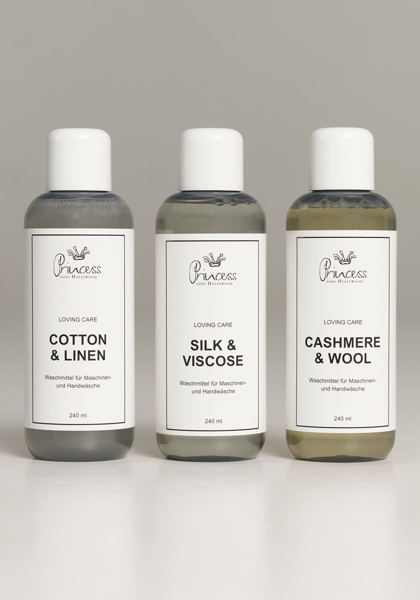 Three bottles of Princess Goes Hollywood Pflegewaschmittel stand side by side on a light surface. Each clear 240 ml bottle has a white cap and label for Baumwolle & Leinen, Silk & Viscose, and Cashmere & Wool.