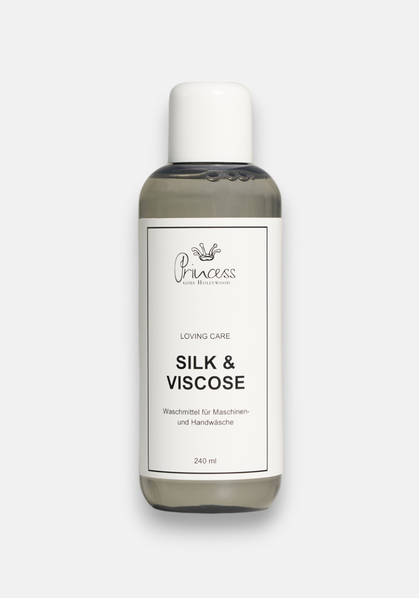 A clear plastic bottle with a white cap holds Princess Goes Hollywood Silk Viscose Pflegewaschmittel. The white label with black text and crown logo describes care for silk and viscose fibers, in German—240 ml, keeps fabrics leuchtend frisch.
