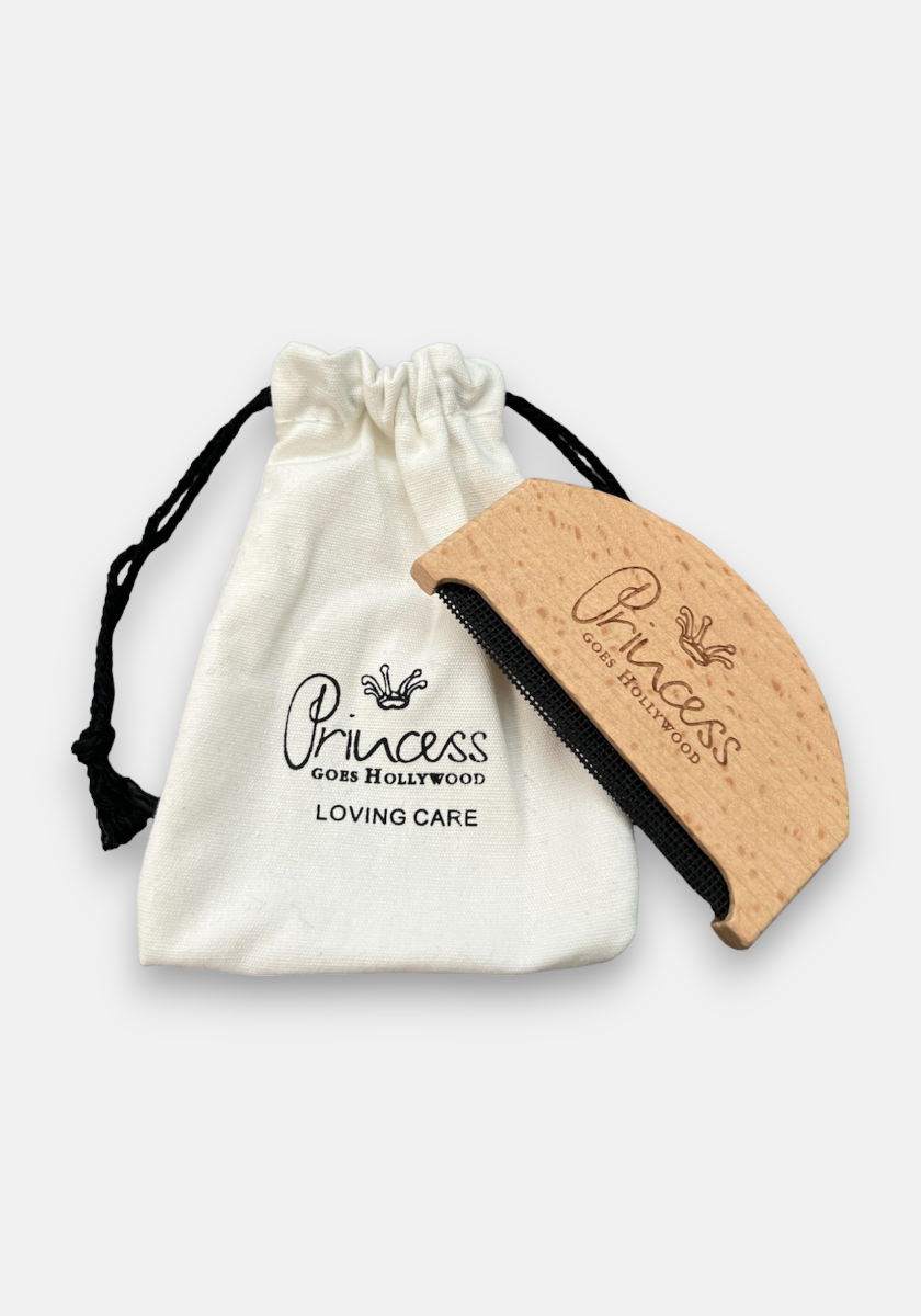 A curved Princess Goes Hollywood Kaschmirkamm aus Buchenholz sits next to a white drawstring pouch with the logo and LOVING CARE print. The set is ideal for gentle detangling and minimizing pilling.