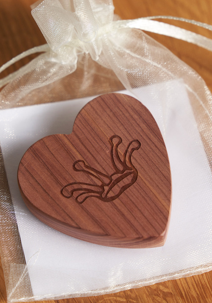 A heart-shaped Zedernholz keepsake by Princess Goes Hollywood, engraved with a crown, rests on a white envelope in an organza gift bag with ribbon—ideal for Mottenschutz in your Kleiderschrank.