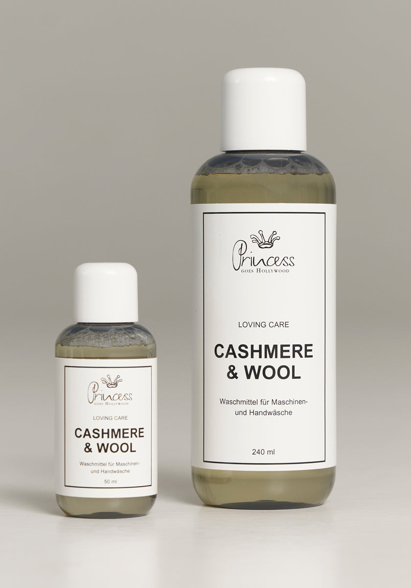 Two bottles of Princess Goes Hollywood Kaschmir & Wolle Pflegewaschmittel stand upright on a light gray surface: the 50 ml bottle is on the left, and the 240 ml bottle is on the right. Both feature white caps and minimalist white labels with black text.