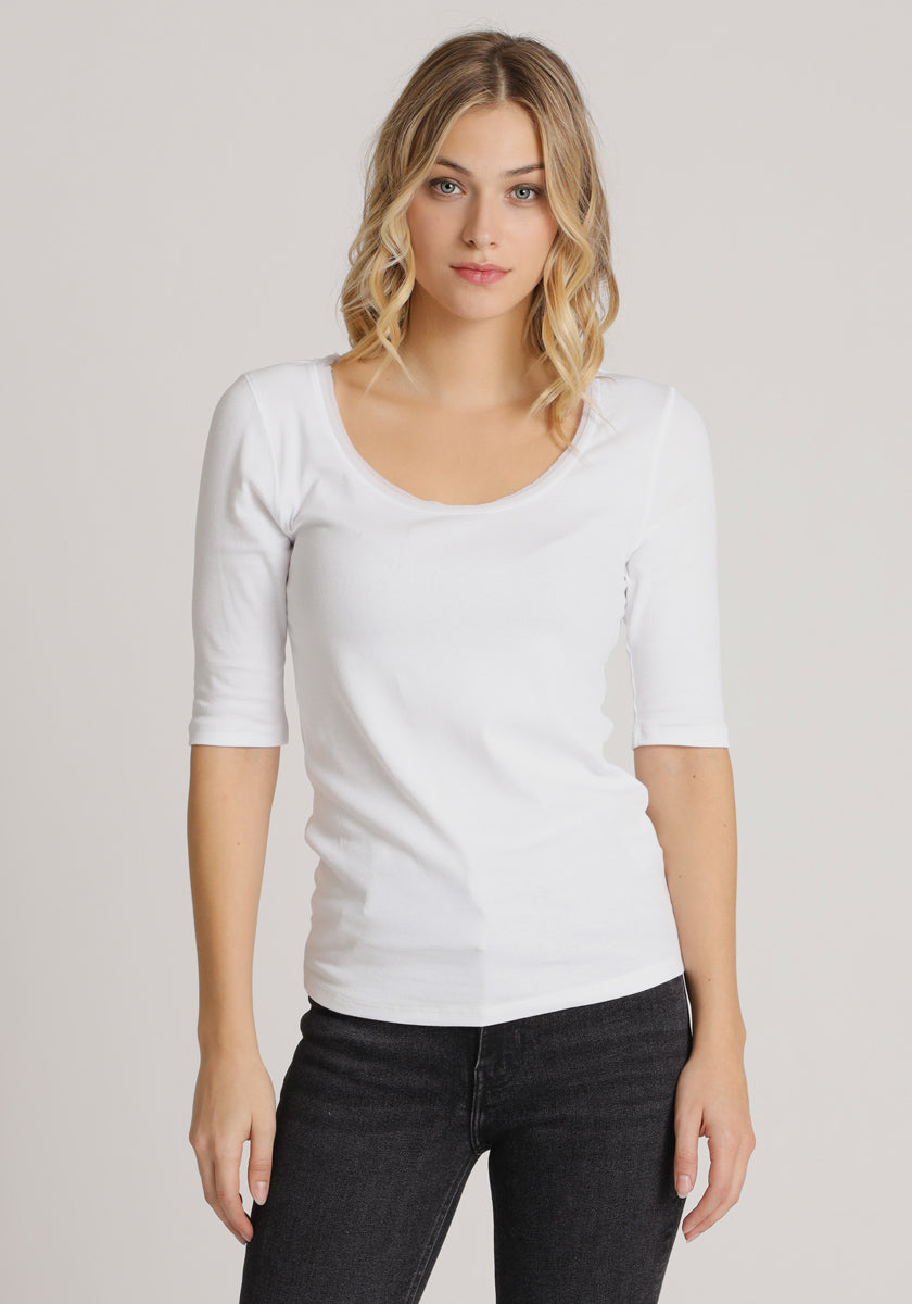 A woman with blonde wavy hair wears a fitted white 3/4-arm Baumwolle shirt by Princess Goes Hollywood and black jeans, standing against a plain light gray background, looking directly at the camera with a neutral expression.