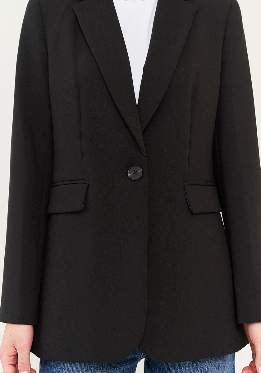 Eine Person trägt einen schwarzen Blazer von Princess Goes Hollywood im schmalen Schnitt mit einem Knopfverschluss aus stretchigem Webstoff über einem weißen Shirt zu blauen Jeans. Das Bild zeigt nur die Kleidung, von den Schultern bis zu den Oberschenkeln.