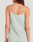 A woman with long brown hair wears a light sage green Bella Dahl Lyocell Trägertop with thin, adjustable straps and frayed edges, paired with matching shorts. She is shown from the back against a plain light background.