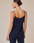A woman with medium skin tone and brown hair in a neat bun, seen from the back, wears a Bella Dahl navy blue V-neck sleeveless camisole with thin straps and matching denim-look pants, standing against a light beige background.