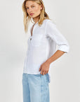 A woman with long blonde hair models an oversized white Hemdbluse by Bella Dahl, crafted from 100% Lyocell, paired with light blue jeans. She poses relaxedly, gazing left against a plain light backdrop.
