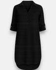 A black, knee-length Lyocell dress by Bella Dahl features a collar, V-neckline, three front buttons, long sleeves with buttoned tabs, and a slightly rounded hi-low hem. Shown against a plain light gray background.