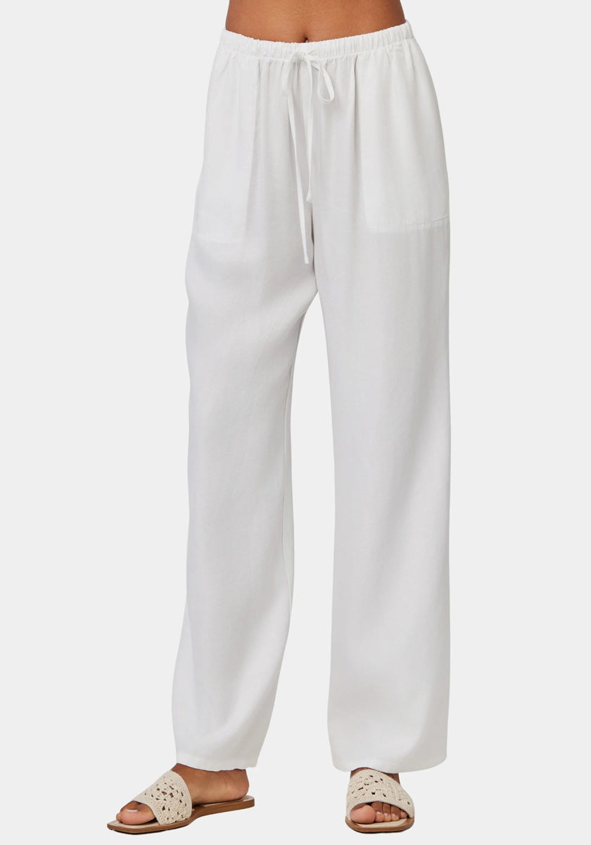 Eine Person trägt eine weite Hose Damen von Bella Dahl mit elastischem Bund und beige Slide-Sandalen mit Cut-out-Details vor weißem Hintergrund. Nur der Unterkörper ist zu sehen – ein lässiger, komfortabler Look.