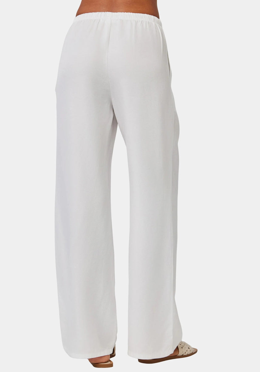 A person is shown from the waist down, wearing Bella Dahls loose-fitting, wide-leg white Lyocell Damenhose with elastischem Bund. The ankle-length pants are paired with open-toed sandals against a plain, light background.