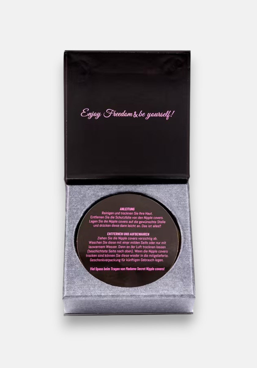 A black box with gray velvet lining, branded Princess Goes Hollywood, is open to reveal round selbstklebend Nipple Covers. The lid says “Enjoy Freedom & be yourself!” in pink script, with Silikon German instructions and pink and white product label.