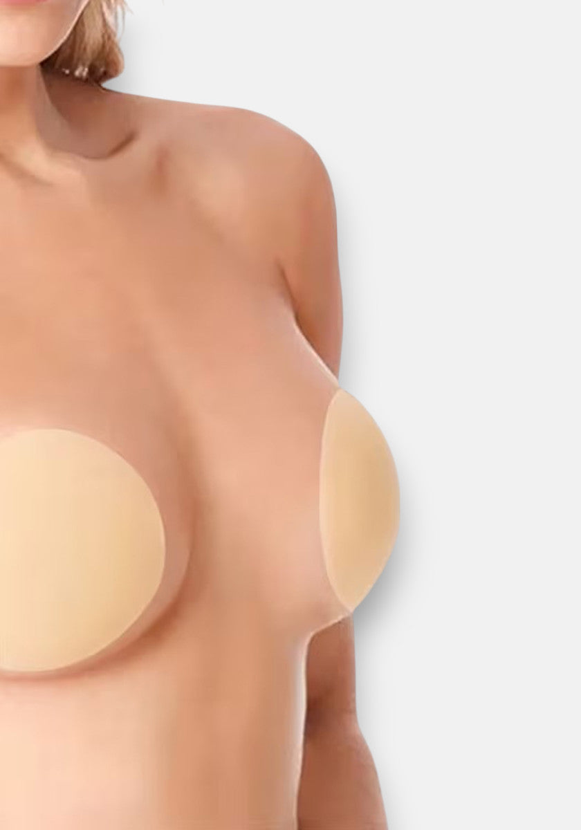 A person’s bare upper torso is shown against a light background, with their breasts covered by large, round, self-adhesive Princess Goes Hollywood Silicone Nipple Covers. The head and lower body are not visible in the image.