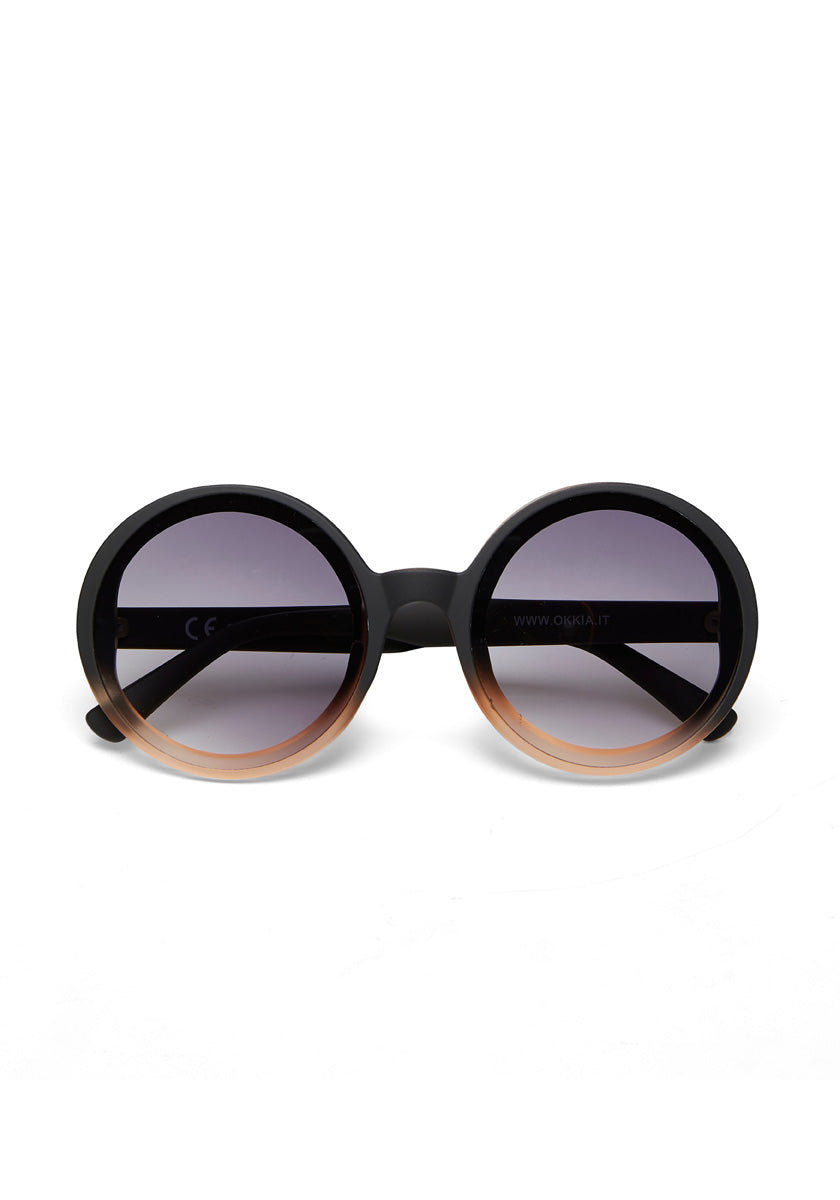 Okkias large, round Oversize-Sonnenbrille features thick black frames fading to light brown and tinted UV 400-Schutz lenses—ideal for stilbewusste Persönlichkeiten. Displayed upright against a white background.