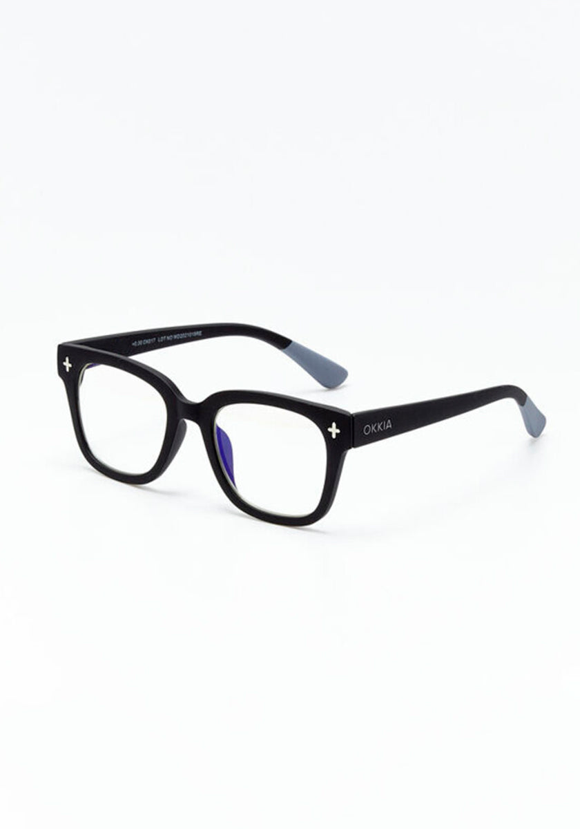 A pair of black rectangular Okkia Bildschirmbrille eyeglasses with clear lenses, white plus symbols on the front corners, and the Okkia logo on the left arm. Gray-tipped temples offer extra comfort. Shown against a plain white background.