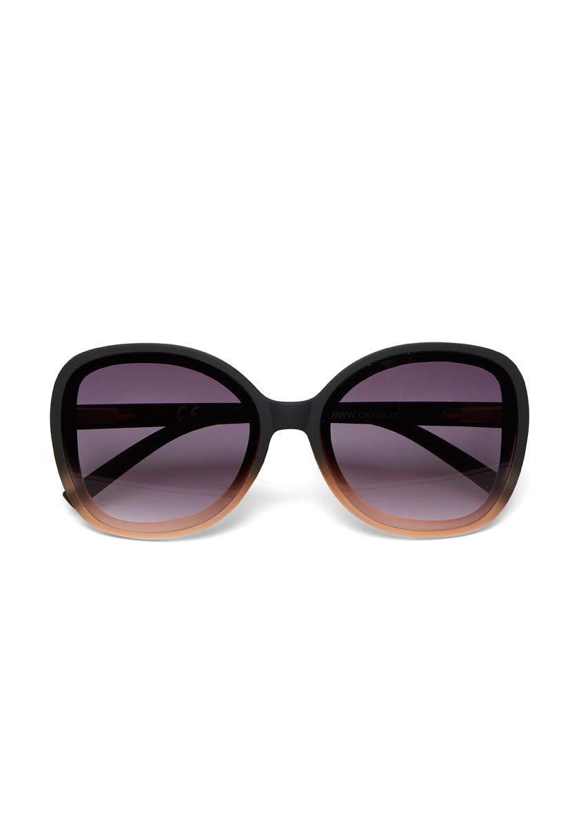 Front view of oversized Okkia Butterfly-Stil Sonnenbrille with rounded square black-to-light brown frames, dark purple UV-Schutz lenses, and visible arms, all set against a white background.