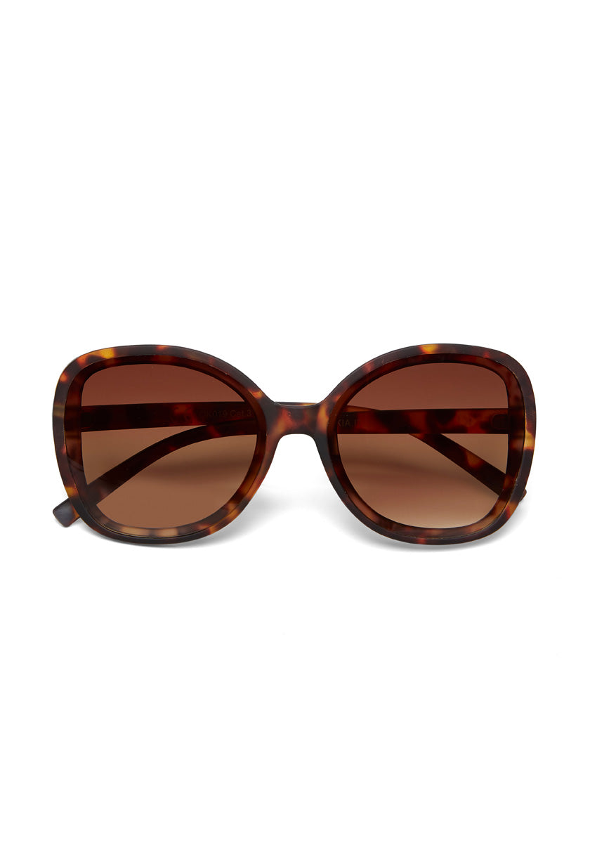 A pair of oversized Okkia ANNA sunglasses with a square butterfly-style frame in tortoiseshell brown and amber. Large, brown-tinted lenses provide full eye coverage and UV protection. Shown on a plain white background.