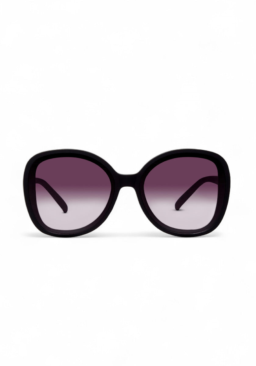 Die breite, übergroße Okkia ANNA Sonnenbrille im Butterfly-Stil besticht mit dicken schwarzen Rahmen und abgerundeten quadratischen Gläsern. Die Verlaufsgläser schützen vor UV-Strahlen und zeigen ein dunkles Lila zu helleren Tönen. Hintergrund: schlicht weiß.