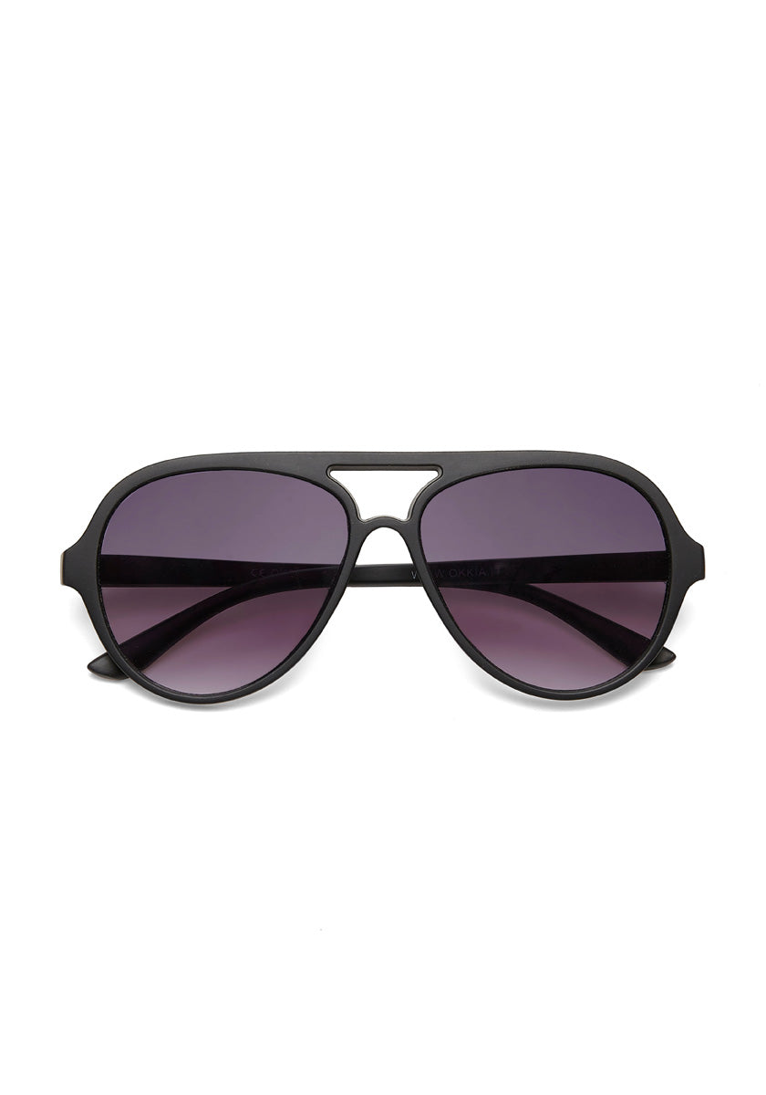 A pair of Okkia black Aviator-Stil sunglasses with large, rounded, dark purple-tinted lenses and a double bridge design, offering UV 400-Schutz, are displayed facing forward on a white background.