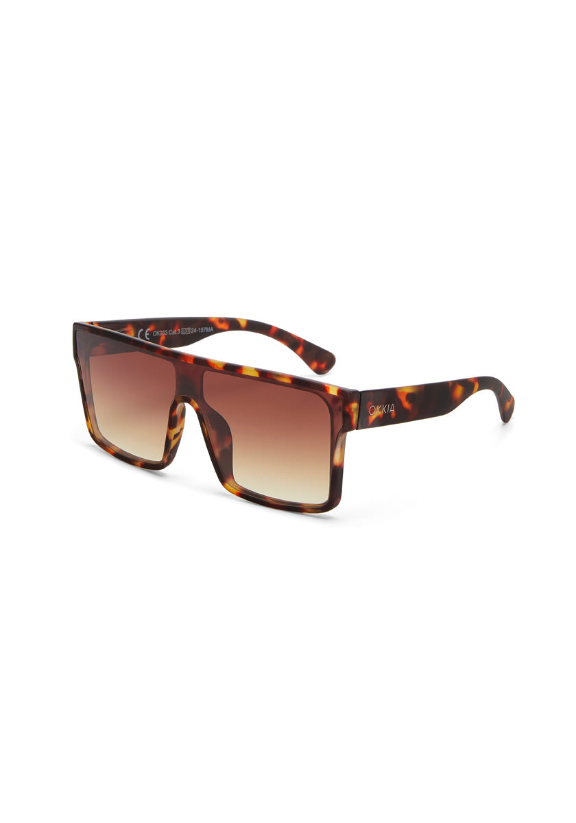 Okkia rectangular sunglasses with thick tortoiseshell frames, gradient brown lenses, and slightly curved temples. The white Okkia logo features on the right arm. UV 400 protection included. Displayed on a white background.
