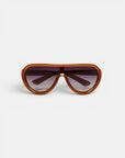 Braune, oval geformte Okkia PANAREA-Sonnenbrille mit einem breiten Kunststoffrahmen, dunkel getönten Gläsern und breiten Bügeln. Dieses moderne und sportliche Modeaccessoire ist vor einem schlichten weißen Hintergrund nach vorne gerichtet abgebildet.