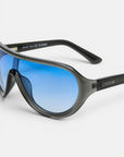 Nahaufnahme einer sportlichen Sonnenbrille mit schwarzem Rahmen und blauen, polarisierten Gläsern mit Farbverlauf. Der Markenname „Okkia“ ist in Weiß auf dem Bügel zu sehen. Vor einem schlichten weißen Hintergrund hebt das Bild das moderne, geschwungene Design und die reflektierenden Eigenschaften der Gläser hervor – was diese auffällige Brille zu einem idealen Modeaccessoire macht.