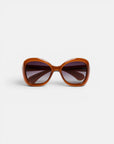 Breite, braune Okkia-Sonnenbrille mit quadratischem Rahmen und dunklen, leicht verlaufenden Gläsern. Die Okkia CLUB-Sonnenbrille ist zusammengeklappt vor einem schlichten weißen Hintergrund abgebildet, direkt von vorne betrachtet, um ihren dicken, glänzenden Rahmen und das retro-inspirierte Design hervorzuheben. Erleben Sie Stil und Komfort zugleich mit dieser polarisierten Sonnenbrille von Okkia, die für zeitlosen Charme geschaffen wurde.