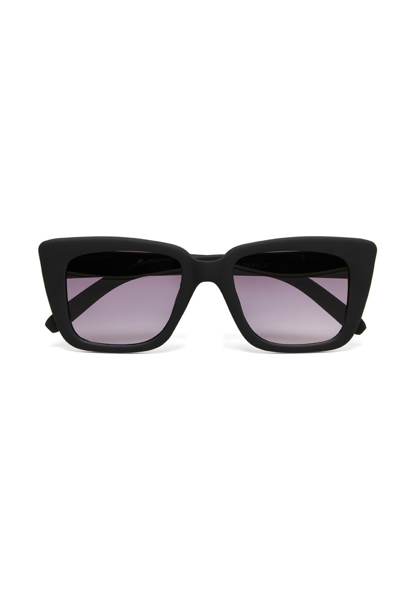 A pair of Okkia black rectangular cat-eye sunglasses with thick frames and gradient dark lenses, fading from black at the top to clear at the bottom, displayed against a plain white background.