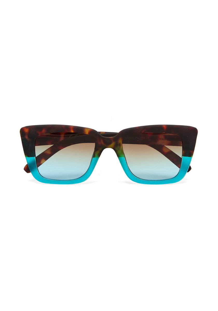 Okkia rectangular sunglasses with a thick frame feature a brown tortoiseshell upper half and bright turquoise lower half. The lenses are lightly tinted, with a gradient from dark at the top to lighter at the bottom.