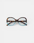 Die Okkia Lesebrille mit übergroßem, rundem Rahmen im Schmetterlingsstil hat eine obere Hälfte aus braunem Schildpatt und eine untere Hälfte in Hellblau. Vor einem schlichten weißen Hintergrund.