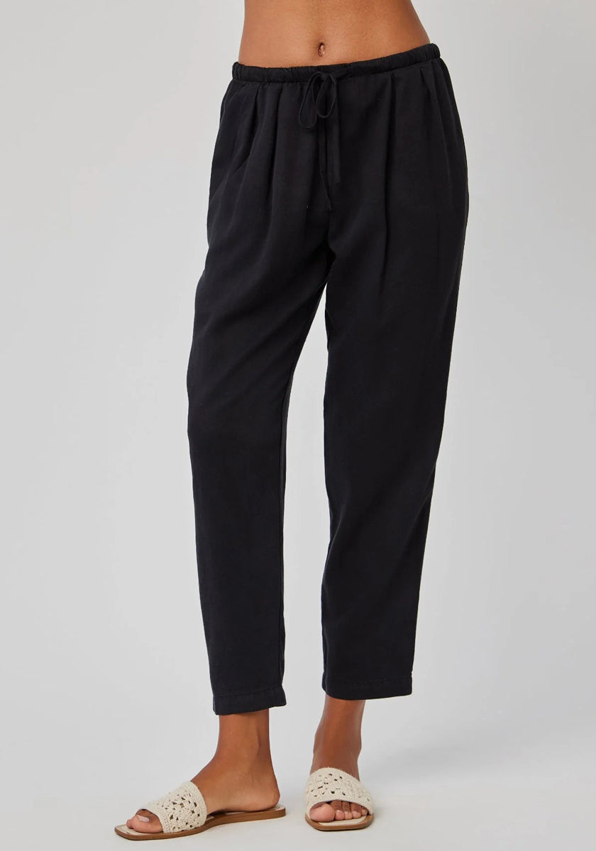 A person wears Bella Dahl’s high-waisted, black Lyocell-Leinen relaxed-fit jogger pants with elastic waistband and drawstring, styled with light open-toe slides. The plain background is light; the image is cropped at the waist.