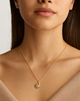 A woman in a V-neck beige top models the Princess Goes Hollywood filigrane Damenkette—a delicate gold chain necklace with a flower-shaped pendant and sparkling stones—shown cropped from shoulders up to highlight the jewelry.