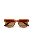 Front view of Okkia unisex sunglasses with a matte amber-brown square frame, matching brown gradient lenses, and cross-shaped metal accents at the hinges. Slightly curved temples and UV 400-Schutz. Shown on a white background.