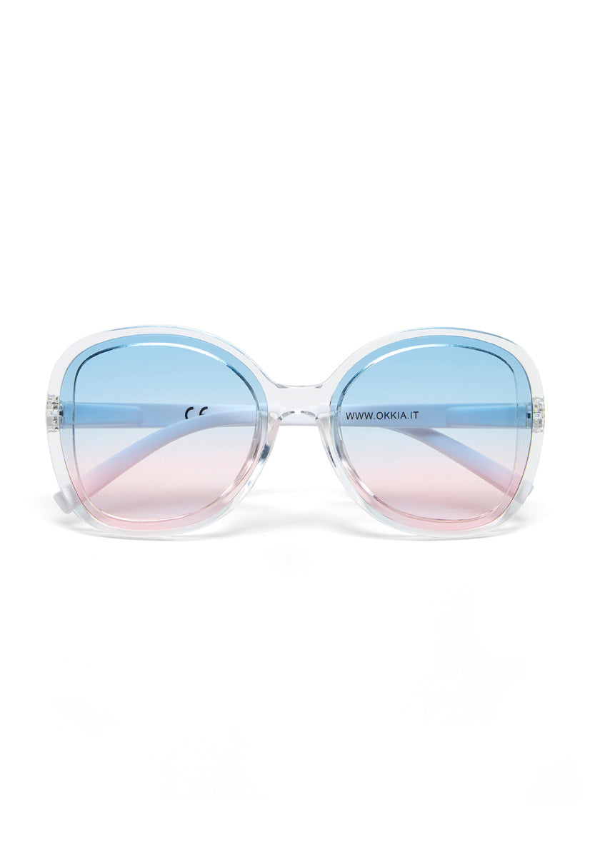 Large, round Okkia sunglasses with transparent frames in a chic butterfly style. Blue-to-pink gradient lenses offer UV protection. www.okkia.it is printed on the right lens. Set against a plain white background.