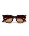 Front view of Okkia Cat-Eye-Sonnenbrille with a thick, brown and amber tortoiseshell frame. The UV-Schutz lenses show a subtle gradient from dark to light brown. Bold, retro-inspired style.