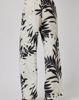 A person wears Bella Dahl Leinenhose with Palmen-Print, featuring wide legs, high waist, relaxed fit, and elastic waistband. Shown from the back against a plain background.