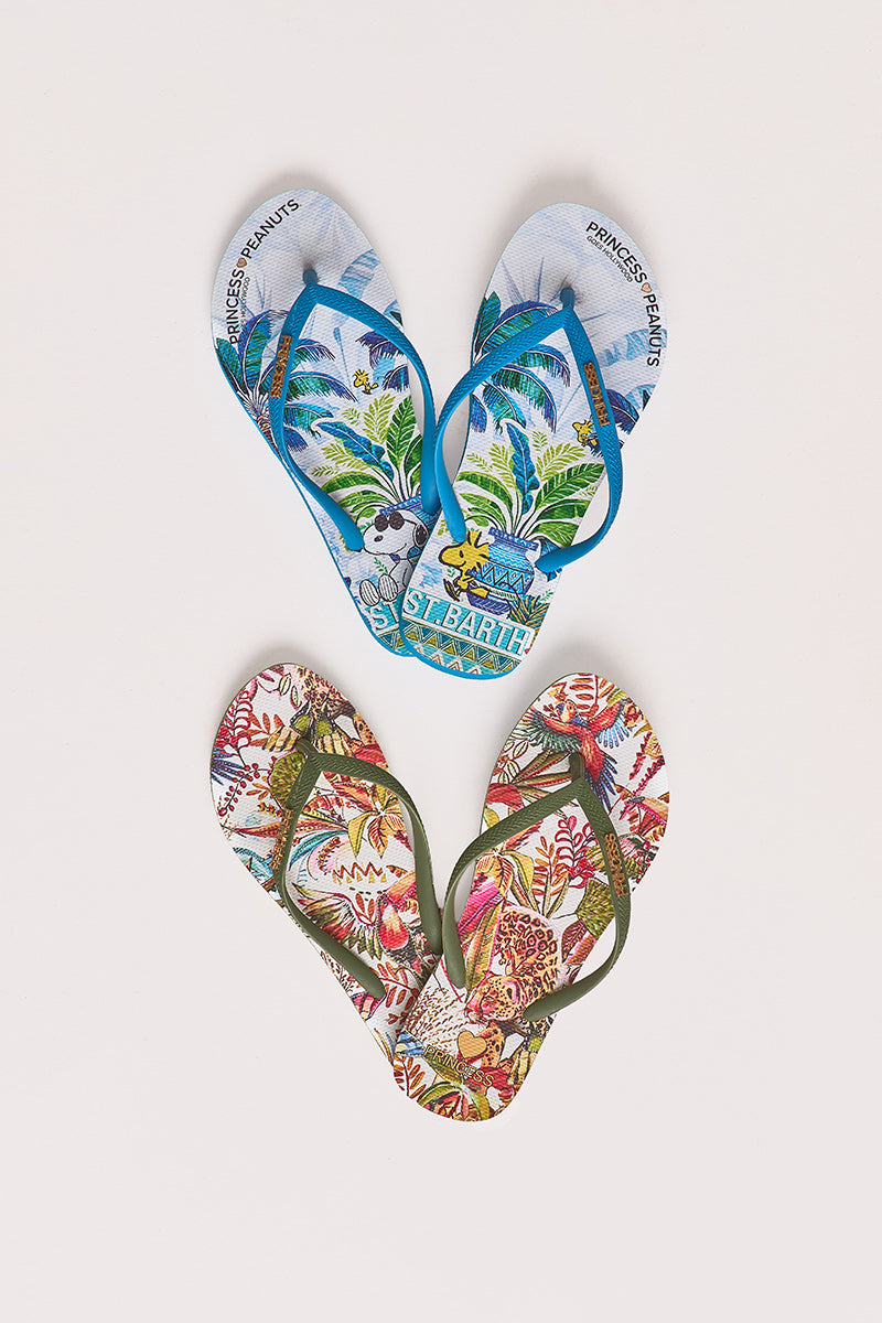 Zwei Paar Flip-Flops. Das obere Paar ist blau mit einem Snoopy-, Woodstock- und Palmenmuster; das untere Paar ist rot und grün mit einem tropischen Pflanzenmuster. Beide sind auf einem weißen Hintergrund angeordnet.