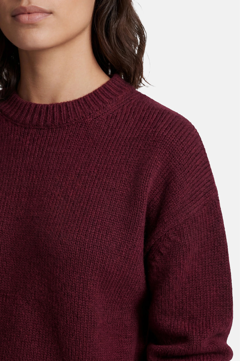 Ein tief burgunderroter Kaschmir-Strickpullover mit geripptem Rundhalsausschnitt, tief sitzenden Schulternähten und einer lockeren Passform.